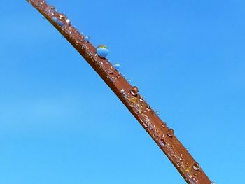 Low angle view of rusty metallic structure against blue sky