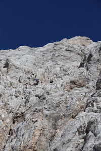 Low angle view of rocks on mountain against clear sky