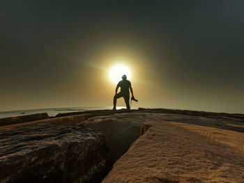 Silhouette man on shore against sky during sunset