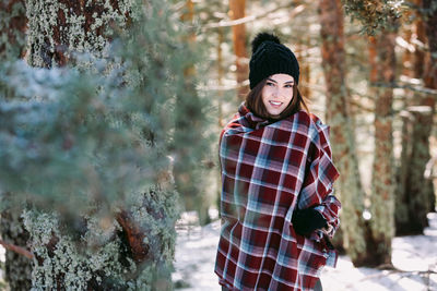 Portrait of smiling young woman standing on snow covered land
