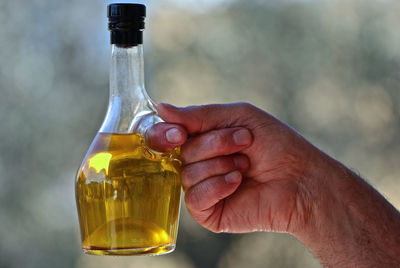 Midsection of person holding glass bottle