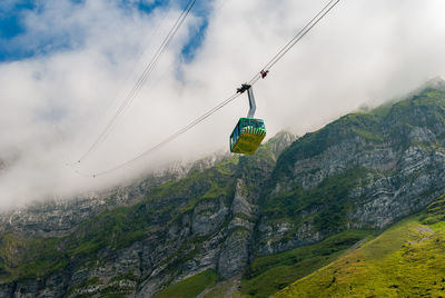 Low angle view of overhead cable car against mountains