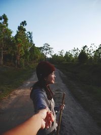 Cropped image of man holding hands with girlfriend on road against clear sky