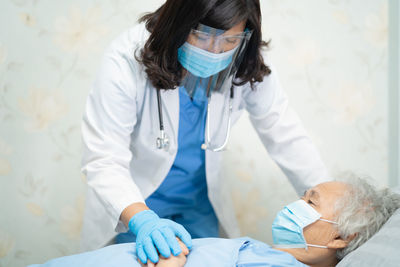 Doctor wearing mask examining patient in hospital