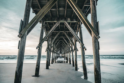 Pier on beach against sky