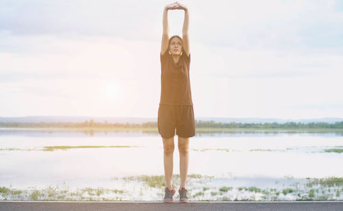 Woman standing by sea against sky