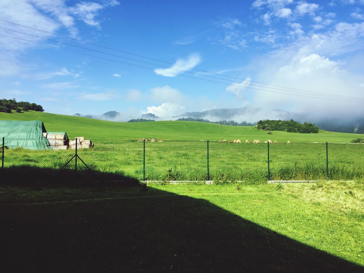 field, landscape, grass, sky, rural scene, tranquil scene, tranquility, agriculture, grassy, scenics, farm, nature, fence, green color, beauty in nature, cloud - sky, electricity pylon, cloud, power line, road