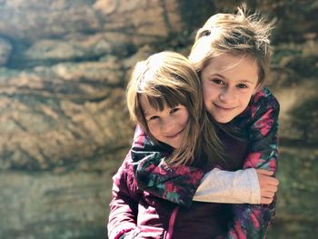 Portrait of smiling siblings against rock