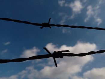 Low angle view of barbed wire against sky