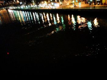 Reflection of illuminated sky on silhouette water at night