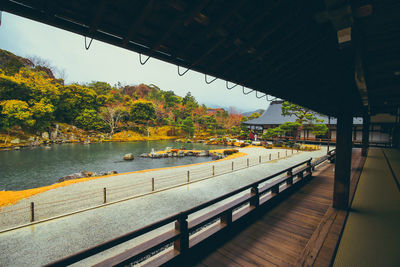 Empty bridge over river against sky