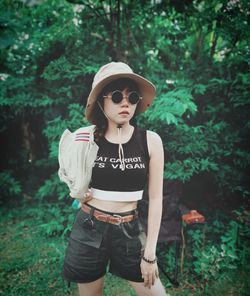 Portrait of young woman standing against trees