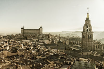 Bell tower of church amidst cityscape against clear sky