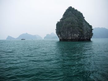 Rock formation in sea against clear sky