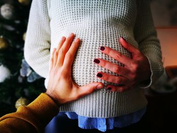 Midsection of pregnant woman with hands on stomach