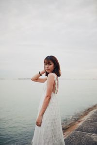 Portrait of woman standing in sea against sky