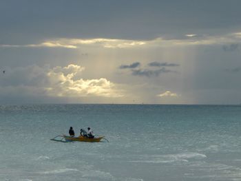 People sitting on sea against sky