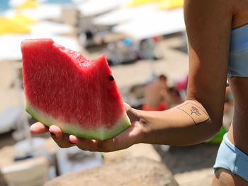 Midsection of teenage girl holding watermelon slice at beach