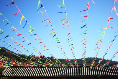 Low angle view of flags hanging against blue sky in lijiang, yunnan province, china