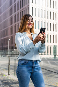 Cheerful businesswoman using mobile phone outdoors
