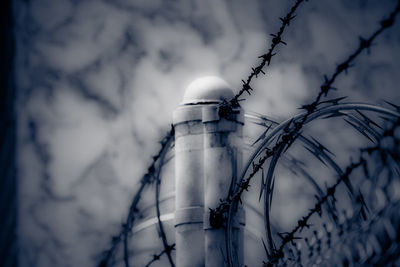 Low angle view of blurred barbwire against grey sky