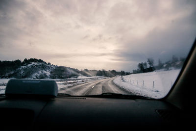 Road seen through car windshield during winter