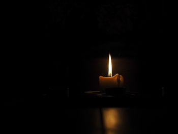 Close-up of lit candle in darkroom