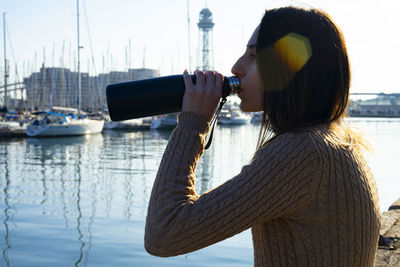 Young woman drinking tea from a black thermos.