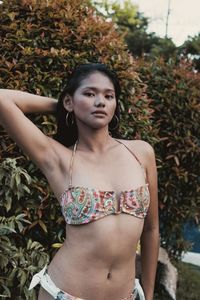 Portrait of young woman standing against plants