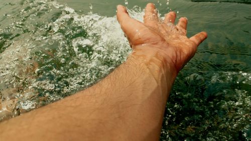 Cropped hand of man touching water