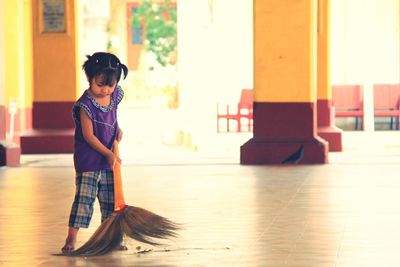 Full length of girl cleaning floor with broom