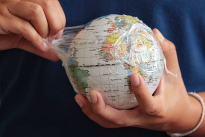 Midsection of man holding globe in plastic bag