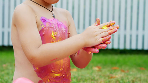 A little child, a four-year-old boy playing, painting with finger paints, decorating himself, in