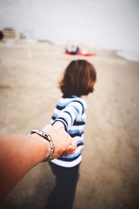 Father holding hand of son on beach