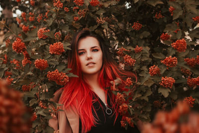 Portrait of beautiful young woman standing against flowering plant