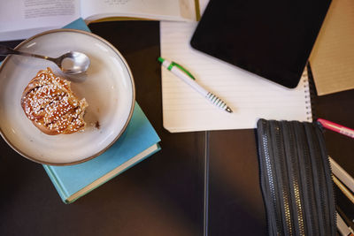 Pastry on plate and studying materials including a digital tablet