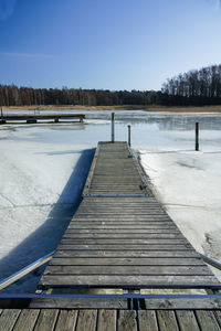 Pier over lake against clear sky during winter