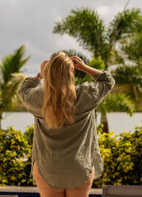 Rear view of woman with arms raised against sky