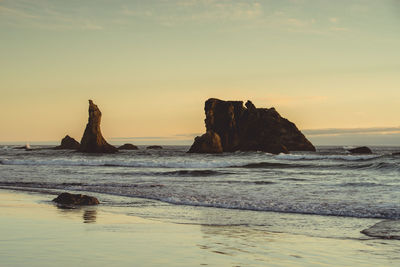 Rock formation on beach against sky during sunset