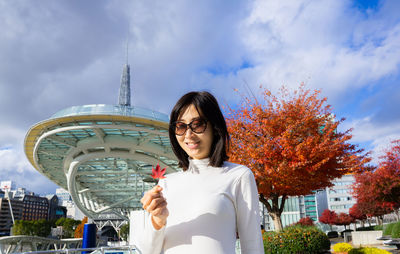 Portrait of young woman standing against sky