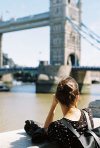 Rear view of woman sitting on bridge