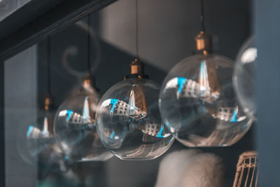 Close-up of illuminated light bulbs hanging from glass ceiling