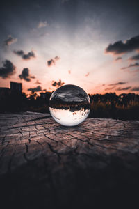 Close-up of crystal ball on water against sky during sunset