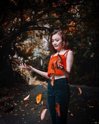 Young woman throwing leaves at park