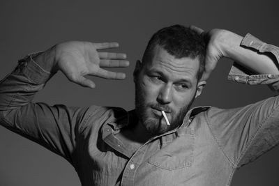 Close-up of man smoking cigarette against gray background