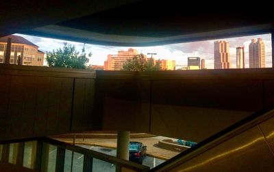 Buildings in city against sky seen through glass window