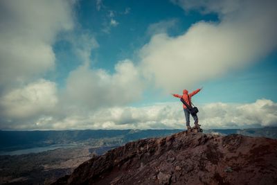 Man standing on rock against sky