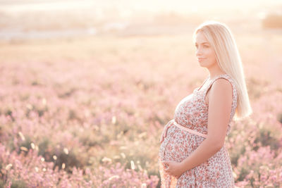 Smiling pregnant woman standing on field