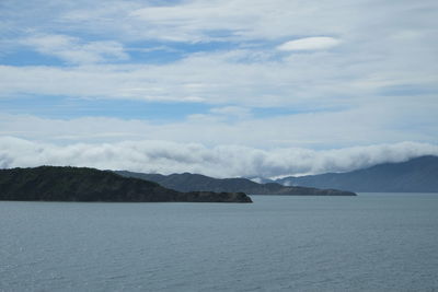 Scenic view of sea and mountains against cloudy sky