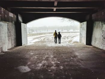 Rear view of people walking in tunnel